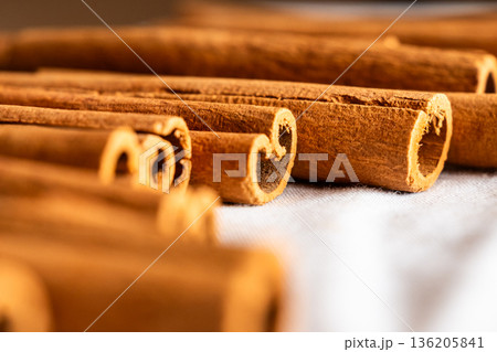 Cinnamon cassia sticks stacked together, showcasing their rich brown color and curled ends. Ideal for culinary and aromatic uses. Cinnamon cassia sticks stacked together, showcasing their rich brown color and curled ends. Ideal for culinary and aromatic uses. 136205841