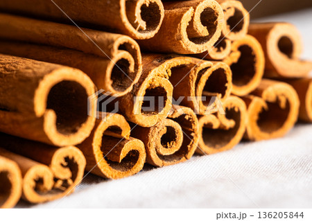 Cinnamon cassia sticks stacked together, showcasing their rich brown color and curled ends. Ideal for culinary and aromatic uses. Cinnamon cassia sticks stacked together, showcasing their rich brown color and curled ends. Ideal for culinary and aromatic uses. 136205844