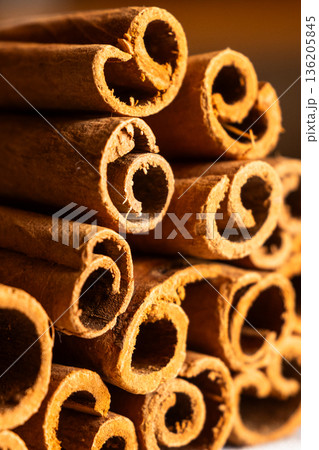 Cinnamon cassia sticks stacked together, showcasing their rich brown color and curled ends. Ideal for culinary and aromatic uses. 136205845