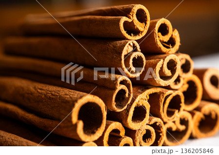Cinnamon cassia sticks stacked together, showcasing their rich brown color and curled ends. Ideal for culinary and aromatic uses. Cinnamon cassia sticks stacked together, showcasing their rich brown color and curled ends. Ideal for culinary and aromatic uses. 136205846