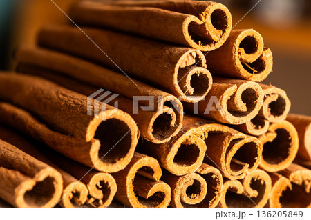 Cinnamon cassia sticks stacked together, showcasing their rich brown color and curled ends. Ideal for culinary and aromatic uses. 136205849