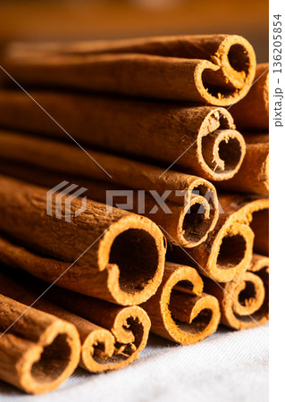 Cinnamon cassia sticks stacked together, showcasing their rich brown color and curled ends. Ideal for culinary and aromatic uses. Cinnamon cassia sticks stacked together, showcasing their rich brown color and curled ends. Ideal for culinary and aromatic uses. 136205854