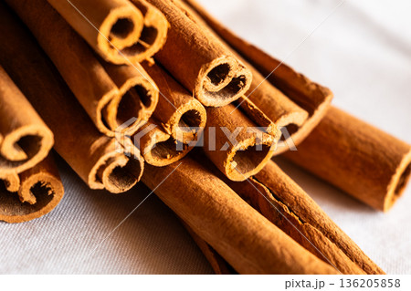 Cinnamon cassia sticks stacked together, showcasing their rich brown color and curled ends. Ideal for culinary and aromatic uses. 136205858