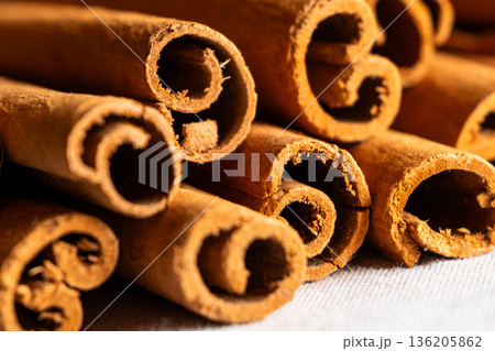 Cinnamon cassia sticks stacked together, showcasing their rich brown color and curled ends. Ideal for culinary and aromatic uses. 136205862