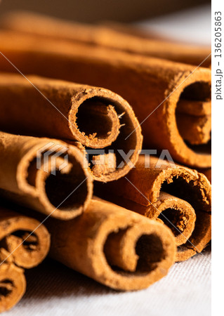 Cinnamon cassia sticks stacked together, showcasing their rich brown color and curled ends. Ideal for culinary and aromatic uses. 136205863