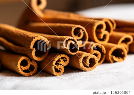 Cinnamon cassia sticks stacked together, showcasing their rich brown color and curled ends. Ideal for culinary and aromatic uses. 136205864