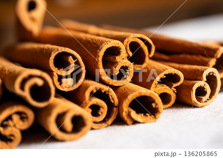 Cinnamon cassia sticks stacked together, showcasing their rich brown color and curled ends. Ideal for culinary and aromatic uses. 136205865