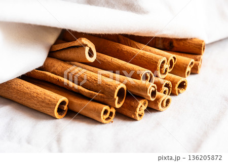 Cinnamon cassia sticks stacked together, showcasing their rich brown color and curled ends. Ideal for culinary and aromatic uses. 136205872