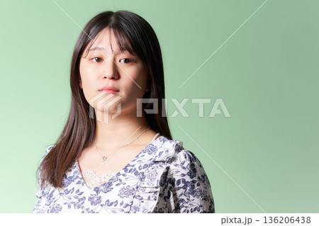 緑背景の前で真剣な表情を見せる20代日本人女性 136206438