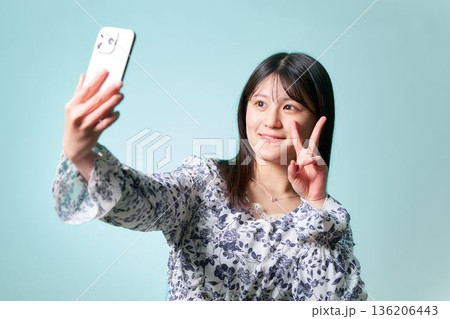 スマートフォンを掲げて笑顔で自撮りをする日本人女性 136206443