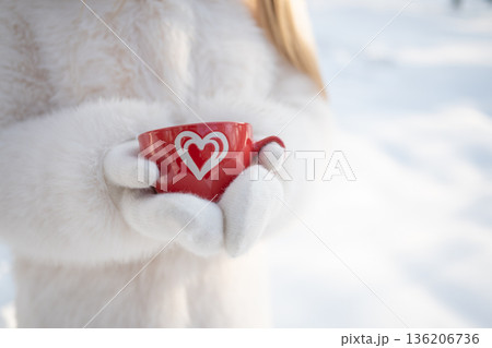 Red cup with hot drink in winter hands 136206736