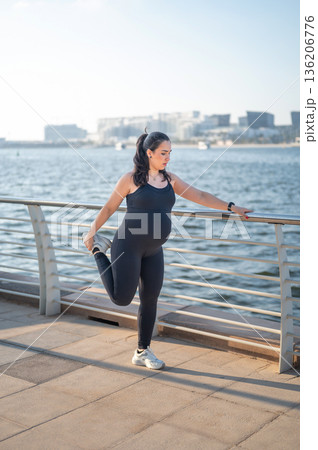 Graceful Prenatal Stretching: Pregnant Woman Balancing By The Water 136206776