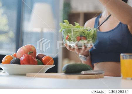 Fit young Asian women in activewear sitting on yoga mat and eating fresh vegetable salad after workout, representing clean eating, fitness lifestyle, wellness routine and health balance. Fit young Asian women in activewear sitting on yoga mat and eating fresh vegetable salad after workout, representing clean eating, fitness lifestyle, wellness routine and health balance. 136206884