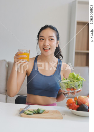 Fit young Asian women in activewear sitting on yoga mat and eating fresh vegetable salad after workout, representing clean eating, fitness lifestyle, wellness routine and health balance. Fit young Asian women in activewear sitting on yoga mat and eating fresh vegetable salad after workout, representing clean eating, fitness lifestyle, wellness routine and health balance. 136206908