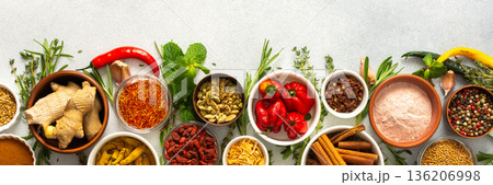 Assorted cooking spices and herbs arranged on a gray surface, featuring natural tones that add depth and aroma to any meal, banner 136206998