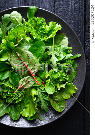 Fresh mix salad leaves arranged on black plate Fresh mix salad leaves arranged on black plate 136207124