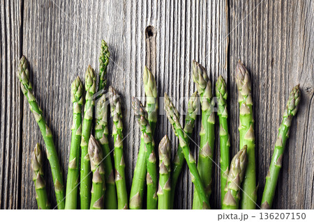 Green asparagus spears arranged in row on rustic wooden surface 136207150