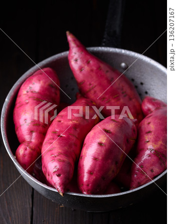Just washed whole sweet potatoes arranged in metal bowl 136207167