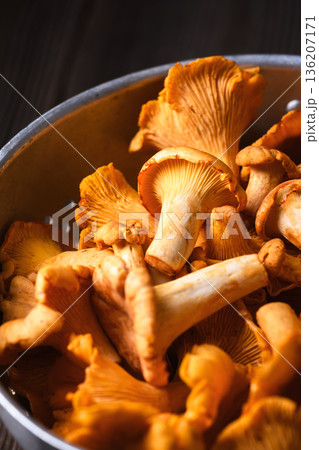 Metal colander filled with fresh chanterelles on rustic background Metal colander filled with fresh chanterelles on rustic background 136207171