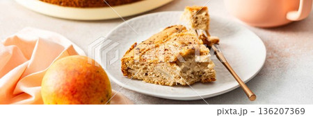 A slice of pear pie sits on a white plate with a fork. A warm coffee cup is next to it. Fresh pears are placed on the table, adding to the scene, banner A slice of pear pie sits on a white plate with a fork. A warm coffee cup is next to it. Fresh pears are placed on the table, adding to the scene, banner 136207369