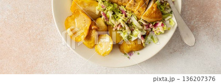 Fresh baked potatoes and chicken breast served with a salad of Chinese cabbage and pink radish make a healthy breakfast option. This meal is prepared at home and offers nutrition, banner 136207376