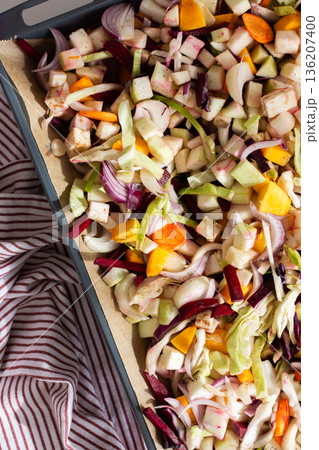 Fresh vegetables are chopped and placed on a baking tray ready for cooking in the oven. Colorful ingredients are showcased, and the setting is a welcoming kitchen Fresh vegetables are chopped and placed on a baking tray ready for cooking in the oven. Colorful ingredients are showcased, and the setting is a welcoming kitchen 136207400