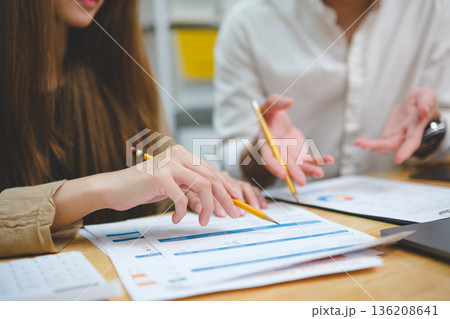 Two people reviewing financial data discussing performance results and analyzing business strategy Two people reviewing financial data discussing performance results and analyzing business strategy 136208641