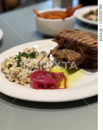 Grilled bread with creamy salad and pickled onions on a white plate, perfect for food background 136208766