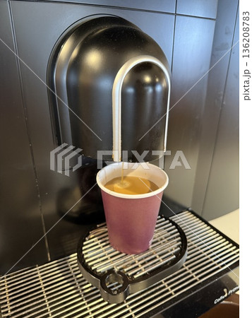 Espresso machine making coffee in disposable cup on black table background from top view 136208783