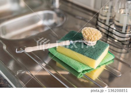 Authentic sustainability concept. Wooden brush and plastic sponge for washing dishes in the kitchen. Eco friendly, zero waste or conscious consumption concept. Authentic sustainability concept. Wooden brush and plastic sponge for washing dishes in the kitchen. Eco friendly, zero waste or conscious consumption concept. 136208851