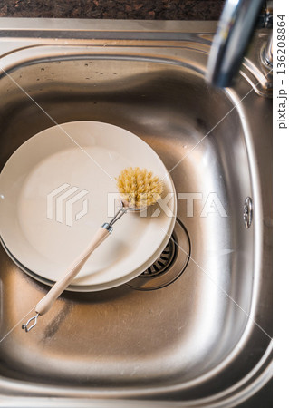 Authentic sustainability concept. Wooden brush for washing dishes in the kitchen sink. Eco friendly, zero waste or conscious consumption concept. 136208864