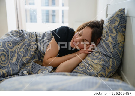 Young woman sleeping on her side in a cozy bedroom Young woman sleeping on her side in a cozy bedroom 136209487