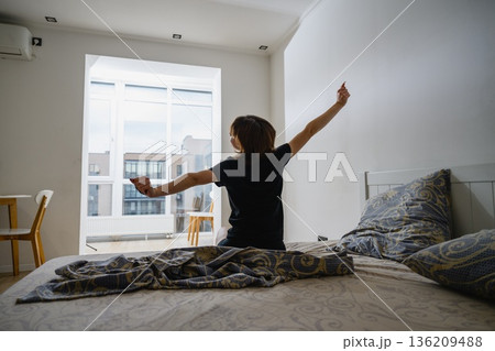 Woman stretching arms after waking up in bedroom Woman stretching arms after waking up in bedroom 136209488
