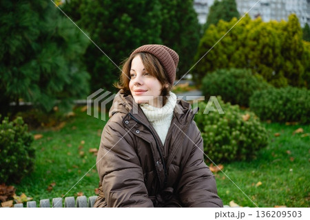 Woman sitting in park during autumn season Woman sitting in park during autumn season 136209503