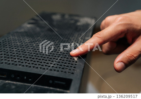 Technician finger indicating dust buildup on computer case surface, highlighting critical need for systematic electronic device cleaning and preservation. Concept of service, repair, cleaning computer 136209517