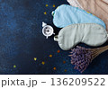 World Sleep Day concept. Bedtime accessories, sleep masks, and classic alarm clock on dark blue wooden background 136209522