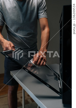 Vertical cropped shot of computer technician wiping glass panel, clearing dust buildup and improving internal airflow for enhanced electronic system performance. Concept of service, cleaning PC. 136209534