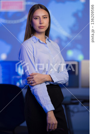 Confident professional in technology office with blue background screens Confident professional in technology office with blue background screens 136209566