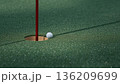 朝露に光るグリーンでカップ際に止まるボールと赤旗の静かな瞬間 136209699