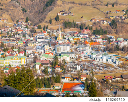 Bad Gastein village from a high viewpoint. Buildings of various styles are nestled in the valley surrounded by mountains and greenery. People visit this area for recreation. Bad Gastein village from a high viewpoint. Buildings of various styles are nestled in the valley surrounded by mountains and greenery. People visit this area for recreation. 136209720