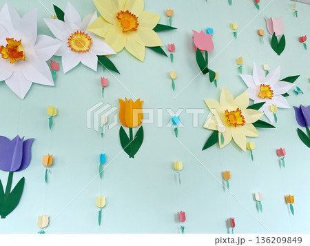 Colorful paper flowers and tulips are beautifully arranged on a light green wall, creating a vibrant and cheerful atmosphere for spring decoration and celebration 136209849