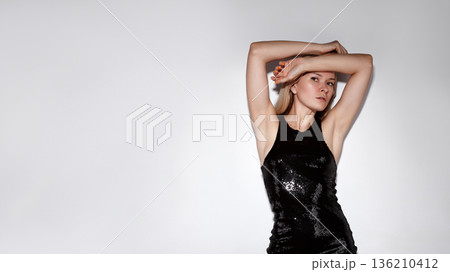 Model With Sequined Attire. Caucasian Female Model Displays Confident Stance In Glossy Evening Wear. Professional Studio Shot Capturing Confident Woman In Shimmering Sequin Dress With Arms Uplifted Model With Sequined Attire. Caucasian Female Model Displays Confident Stance In Glossy Evening Wear. Professional Studio Shot Capturing Confident Woman In Shimmering Sequin Dress With Arms Uplifted 136210412