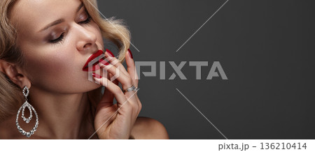 Luxurious Closeup Of Her Face. Charming Lady With Sparkling Accessories And Bold Lipstick. Stylish Caucasian Woman With Shimmering Makeup And Elegant Adornments. Beauty Cosmetic Content, Copy space Luxurious Closeup Of Her Face. Charming Lady With Sparkling Accessories And Bold Lipstick. Stylish Caucasian Woman With Shimmering Makeup And Elegant Adornments. Beauty Cosmetic Content, Copy space 136210414