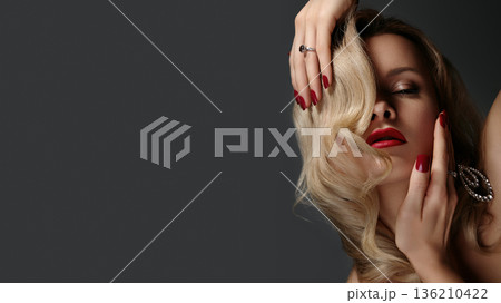 Blonde Caucasian Woman Hand Covering Face Sensually, Red Nails And Statement Ring, Gloss Lipstick, Wavy Curls, Moody Studio Shadows, Seductive Closeup Capturing Intrigue And Texture Blonde Caucasian Woman Hand Covering Face Sensually, Red Nails And Statement Ring, Gloss Lipstick, Wavy Curls, Moody Studio Shadows, Seductive Closeup Capturing Intrigue And Texture 136210422