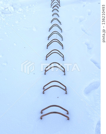 A row of metal bike racks covered in deep snow A row of metal bike racks covered in deep snow 136210493