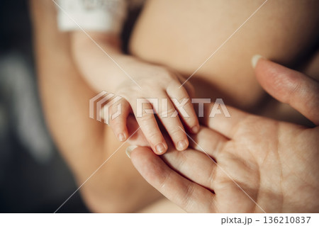 A baby's hand is being held by a woman's hand 136210837
