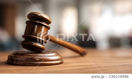 Wooden gavel sits on a wooden base. The gavel is brown and has a wooden handle 136210996