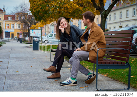 Man and woman talking on bench in city park Man and woman talking on bench in city park 136211074