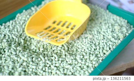 Green tea cat litter in a vibrant tray with a yellow scoop, showcasing eco-friendly pet care solutions and innovative materials for responsible pet ownership 136211563