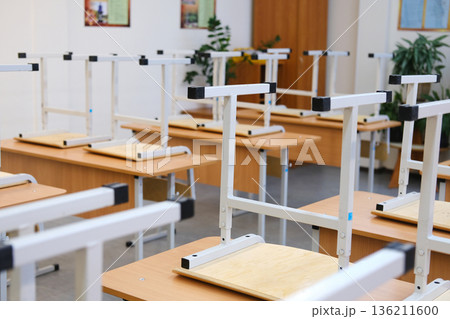 Classroom with raised chairs and empty desks, showcasing a tidy educational environment, symbolizing the end of the school day and the concept of school education Classroom with raised chairs and empty desks, showcasing a tidy educational environment, symbolizing the end of the school day and the concept of school education 136211600